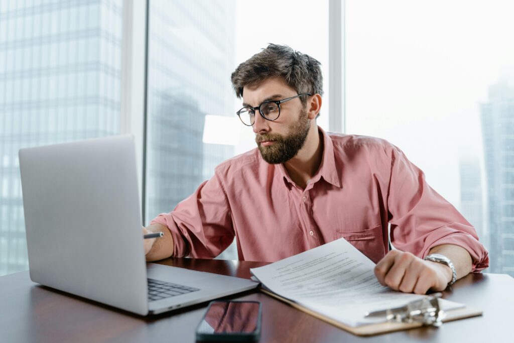 MAN WORKING ON LAPTOP WITH NOTEBOOK -DIGITAL MARKETING JOB